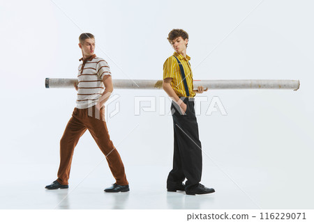 Professional and personal competition. Two retro style young man carrying giant tube and looking at each other with suspicion, isolate on white background. Neighbors. Professional and personal competition. Two retro style young man carrying giant tube and looking at each other with suspicion, isolate on white background. Neighbors. 116229071