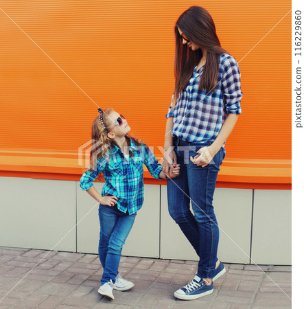 Stylish mother and child daughter together, happy mom with kid girl in casual clothing in the city 116229860