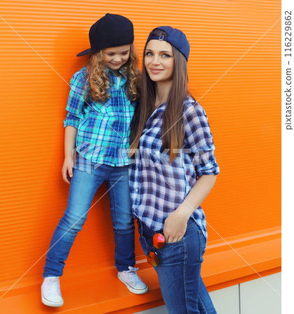 Stylish mother and child daughter together, happy mom with kid girl in casual clothing in the city 116229862