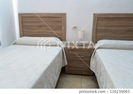 Hotel room interior with white beds, simple comfortable apartment, white bedding, minimal furniture 116230065