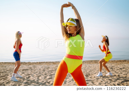 Smiling dancers in colorful swimsuits are dancing on beach ?oncept of sports, aerobics. Active sport 116230222