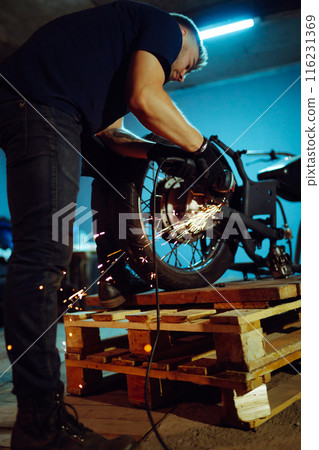 Motorcycle repair. Disassembled motorcycle. Expert works with electric welding of metal. Instruments 116231369