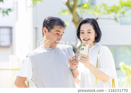 A middle-aged couple looking at a smartphone together A middle-aged couple looking at a smartphone together 116231770