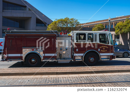 San Francisco Fire Department fire engine parked on a city street, red vehicle with San Francisco Fire Dept. on side. Modern building and blue sky in background. San Francisco Fire Department fire engine parked on a city street, red vehicle with San Francisco Fire Dept. on side. Modern building and blue sky in background. 116232074