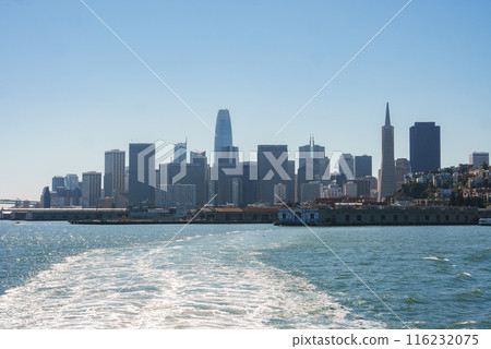 Daytime view of San Francisco skyline from the water, showing iconic buildings like Transamerica Pyramid and Salesforce Tower. Serene waterfront scene under clear blue sky. 116232075