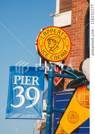 Bright blue Pier 39 banner against clear sky, with Lappert's Ice Cream logo and other signage, brick building in urban setting, location in San Francisco. 116232177