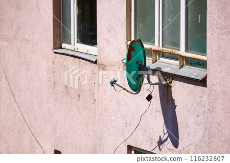 Old rusty satellite dish on the wall at sunny day 116232807