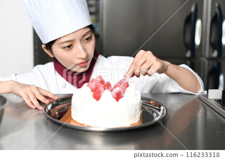 A female pastry chef preparing a whole cake A female pastry chef preparing a whole cake 116233318