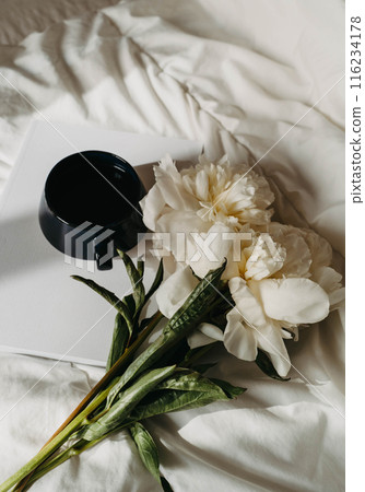 Bouquet of white peony flowers, magazine, cup of tea on white bad textile Bouquet of white peony flowers, magazine, cup of tea on white bad textile 116234178