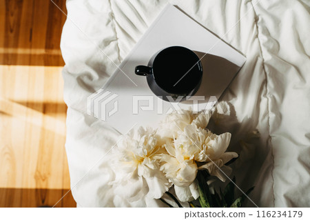 Bouquet of white peony flowers, magazine, cup of tea on white bad textile Bouquet of white peony flowers, magazine, cup of tea on white bad textile 116234179