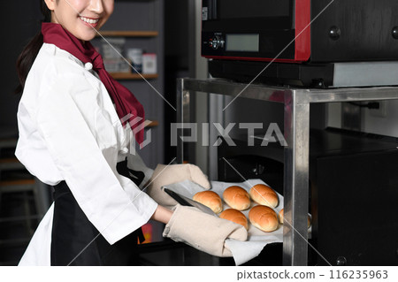 Young woman preparing bread in the oven in the kitchen Young woman preparing bread in the oven in the kitchen 116235963