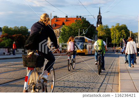 Scenic Dresden cityscape may people riding bikes tram crossing Augustus bridge Elbe river Holy Trinity church Cathedral sunset background. Healthy lifestyle Europe city Germany Saxony capital trip 116236421