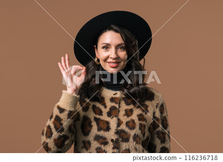 Mature woman with OKAY sign, ok gesture. Happy lady, correct choice on beige 116236718