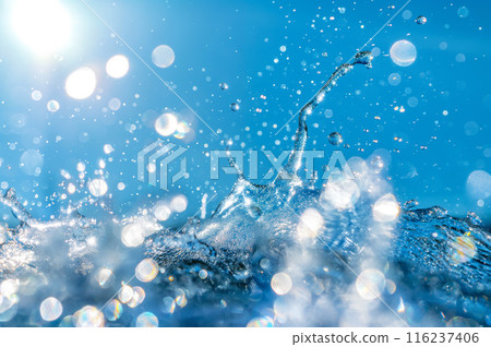 Sun and transparent beautiful water splashes against the background of blue sky 116237406