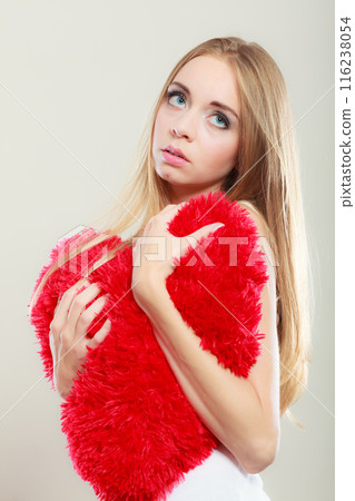 Sad unhappy woman holding red heart pillow 116238054
