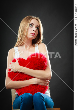 Sad unhappy woman holding red heart pillow 116238055