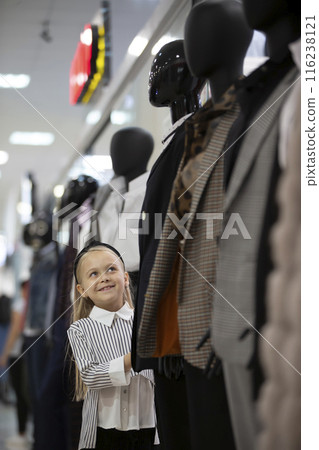 A little girl in the middle of a dummy in a store. A little girl in the middle of a dummy in a store. 116238121