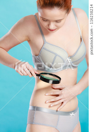 Woman using magnifying glass to examine her moles skin Woman using magnifying glass to examine her moles skin 116238214
