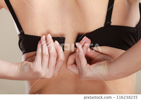 Woman dressing up her bra rear view Woman dressing up her bra rear view 116238235