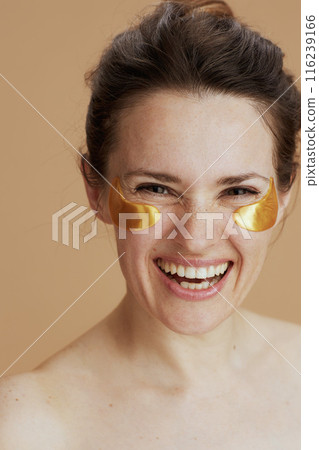 happy young woman with eye patches against beige background 116239166