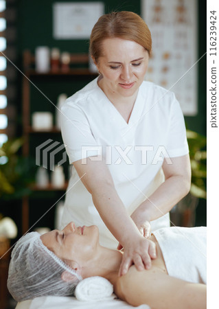 massage therapist massaging clients shoulder on massage table 116239424