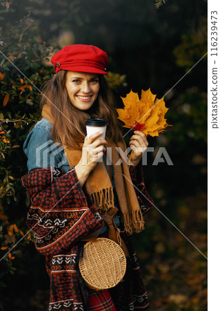happy elegant woman in red hat with autumn leafs and scarf 116239473