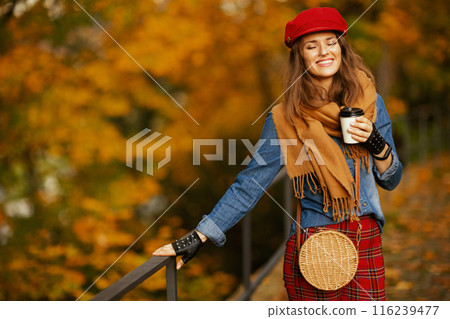 relaxed modern 40 years old woman in jeans shirt and red hat 116239477