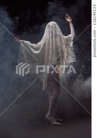 Unrecognizable woman covered in lace veil with raised arms 116240119