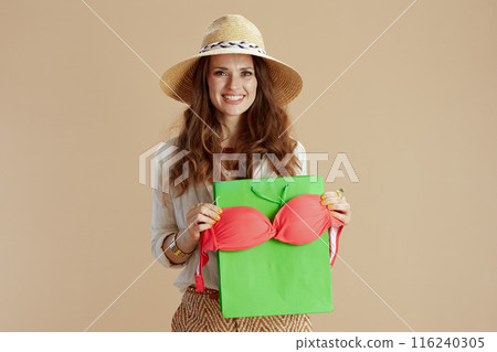 smiling woman in blouse and shorts against beige 116240305