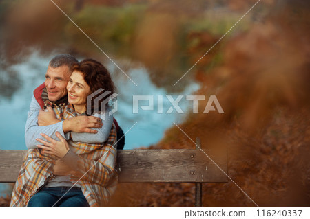 smiling stylish family in park embracing while sitting on bench 116240337