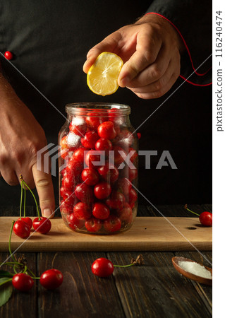 A chef adds lemon to a jar of cherries before canning. The concept of making a delicious compote from sweet cherries. Advertising space A chef adds lemon to a jar of cherries before canning. The concept of making a delicious compote from sweet cherries. Advertising space 116240474