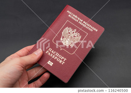 Russian travel passport in a woman's hand on a black background, sanctions, emigration, immigration, tourism concept 116240500