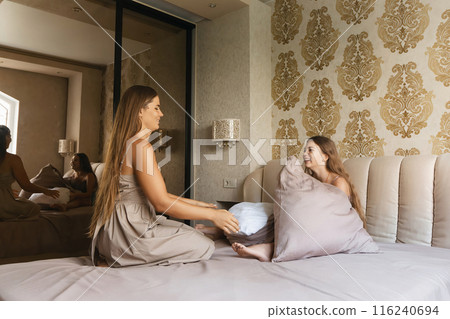 mom and daughter playing with pillows on a bed 116240694