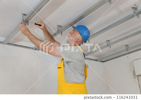 Senior adult worker fixing aluminum batten for gypsum ceiling 116241031