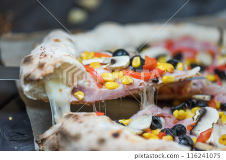 Delicious pizza slices with pepperoni, olives, ham, mushrooms, red pepper and corn, americano style 116241075