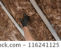 Worker hand in glove apply insulation for gypsum ceiling 116241125