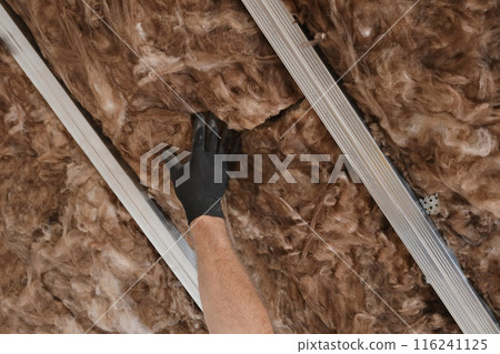 Worker hand in glove apply insulation for gypsum ceiling Worker hand in glove apply insulation for gypsum ceiling 116241125