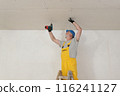 Senior adult worker fixing gypsum ceiling using screwdriver 116241127