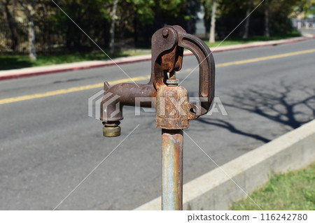 Old rusty faucet on the street, metal tap in a public in the city, rustic industrial landscape 116242780
