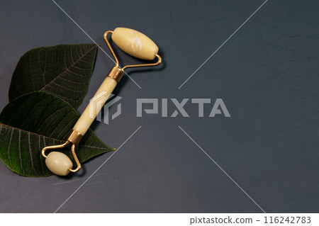 Gua Sha face tool, green stone massage roller on a dark background with copy space, spa background with place for text, skin care 116242783