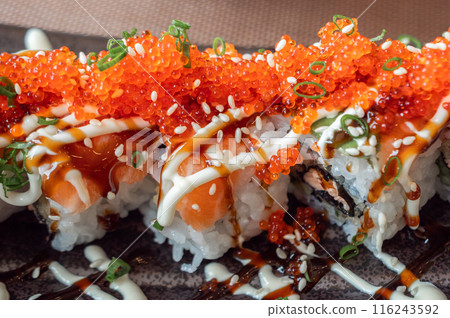 Close up of salmon and tobiko sushi rolls with sesame seeds and green onions. Close up of salmon and tobiko sushi rolls with sesame seeds and green onions. 116243592
