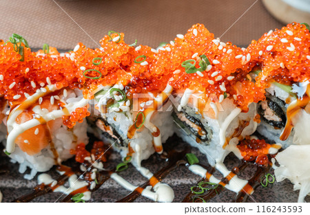 Close up of salmon and tobiko sushi rolls with sesame seeds and green onions. 116243593