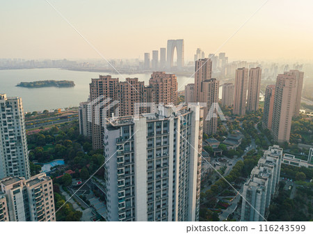 An aerial view of a modern city skyline at sunset, showcasing numerous high-rise buildings. 116243599