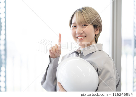A young woman with short blonde hair wearing work clothes and holding a helmet (pointing, free hair color, working in your own way, work environment) A young woman with short blonde hair wearing work clothes and holding a helmet (pointing, free hair color, working in your own way, work environment) 116246994