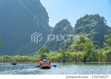 Tourists on a boat tour of Ninh Binh in a rowboat on a river in a valley in Hanoi, Vietnam 116248877