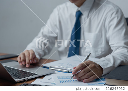 businessman holding pen to analyze data, graphs and market reports of business and growth trends. businessman holding pen to analyze data, graphs and market reports of business and growth trends. 116248932