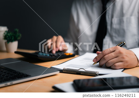 Professional calculating finances on a calculator with documents, laptop and smartphone on desk Professional calculating finances on a calculator with documents, laptop and smartphone on desk 116249211