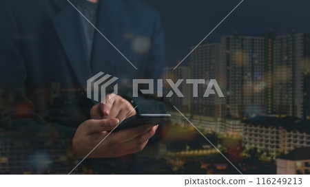 Hands holding a smartphone with a blurred urban Double exposure of Night city. Real estate concept business, home insurance and real estate protection 116249213