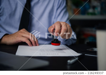 Man stamping approval of work finance banking or investment marketing documents on desk.. 116249337