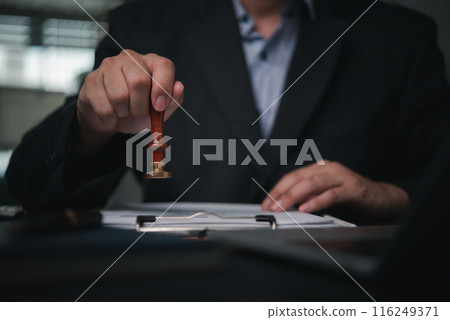 hand is pressing seal onto a document, signifying confidentiality and stamping approval of work finance banking or investment of an agreement. hand is pressing seal onto a document, signifying confidentiality and stamping approval of work finance banking or investment of an agreement. 116249371